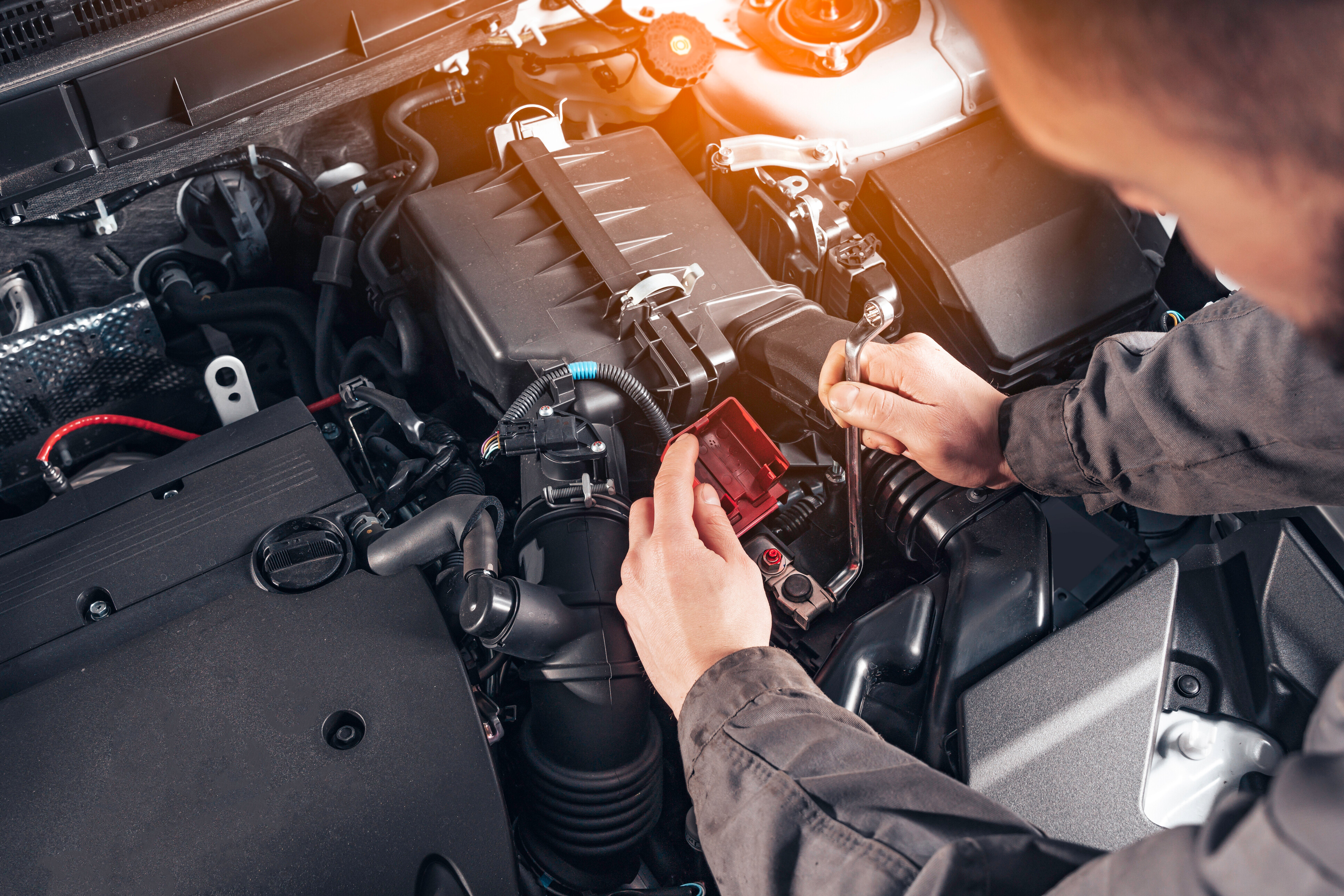 Car battery replacement cost - mechanic installing a new battery in the engine bay