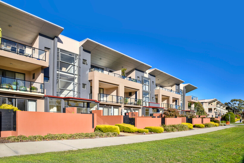 Multi-story apartment units with balconies and landscaped walkways. - apartment vs house