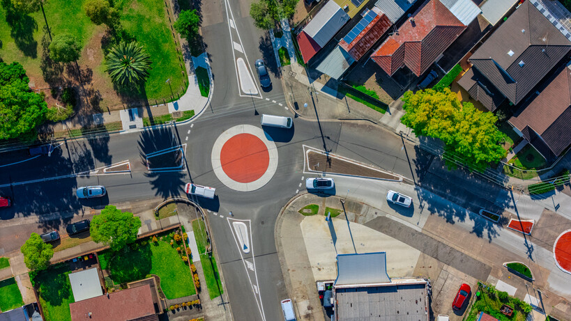Aerial view of a residential roundabout with cars and surrounding houses. - house vs apartment