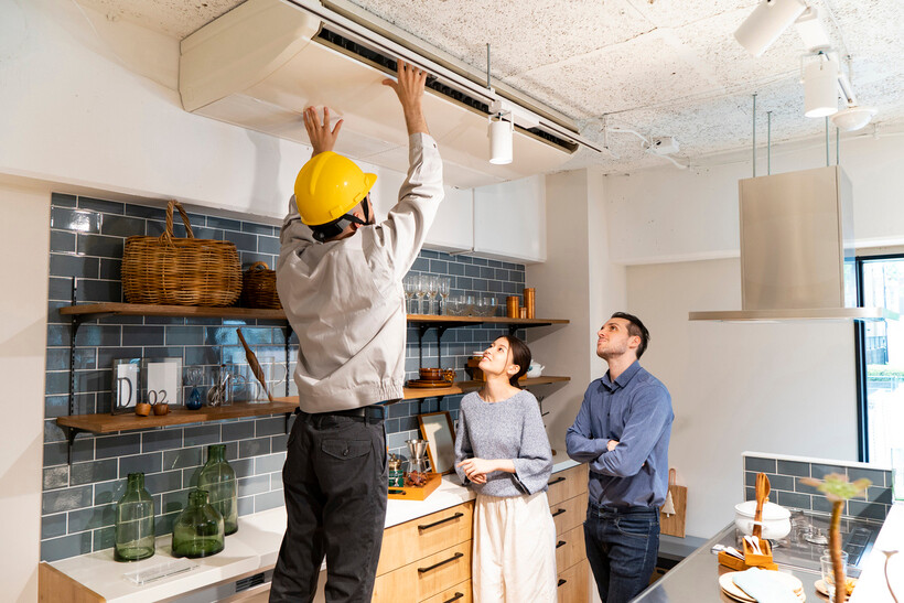 Maintenance worker repairing an air conditioning unit in an apartment. - apartment vs house