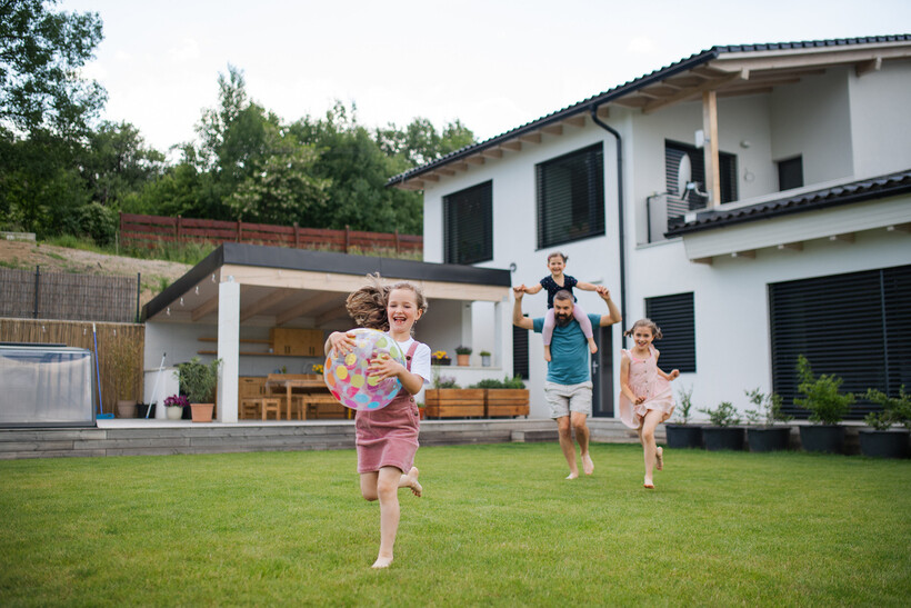 Children running and laughing with their father outside a two-story house. - house vs apartment