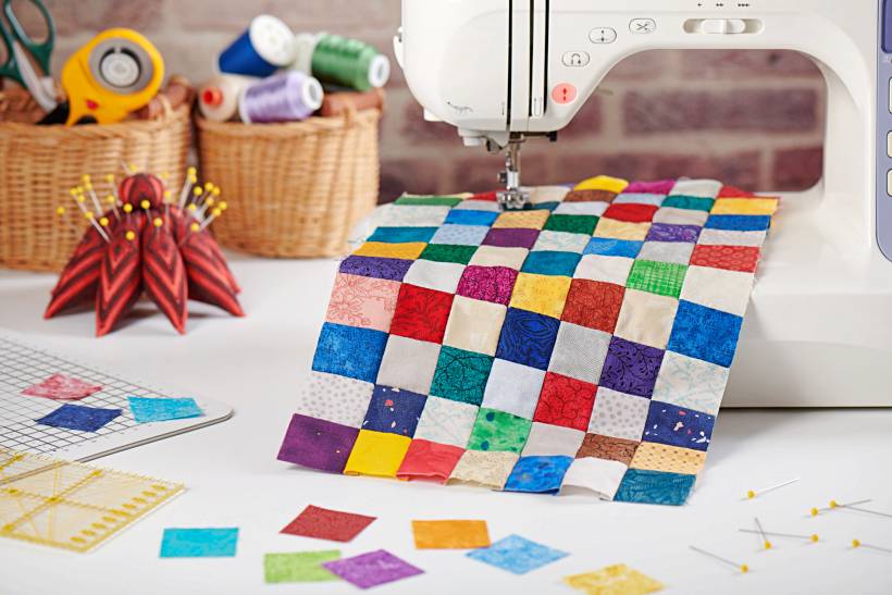 how to make money sewing - Quilting setup with fabric swatches, sewing supplies, and a machine in use
