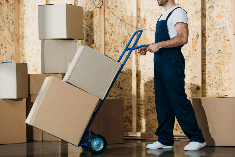 Moving professional transporting packed boxes with a blue hand trolley. - hand trolley vs dolly