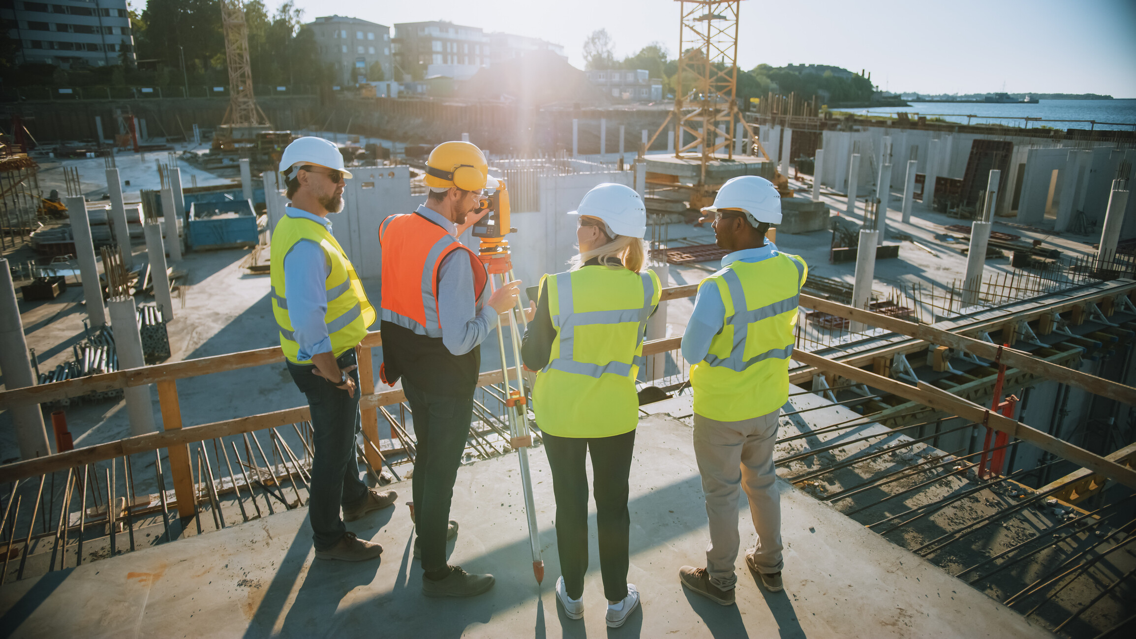 Construction team including a building surveyor using a theodolite