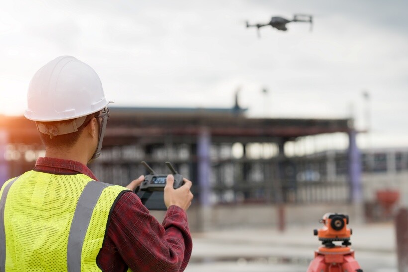 A surveyor using a drone for aerial inspection and site measurement