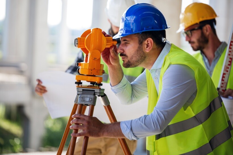 Building surveyor using a theodolite to measure structural levels
