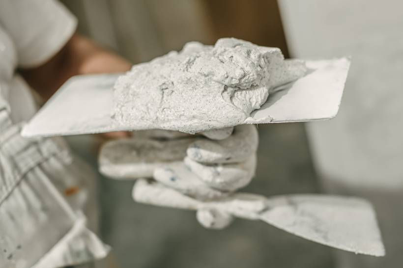 A construction worker holding a trowel covered in fresh mortar, ready for application - lime mortar vs cement mortar