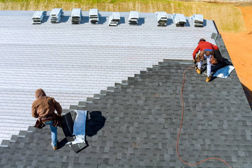 slate vs tile roof - Roofing contractors laying shingles in a staggered pattern on a residential building