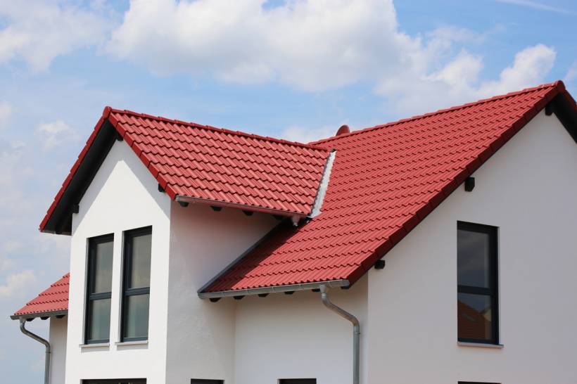 slate vs tile roof - Modern white house with a red tiled roof under a partly cloudy sky