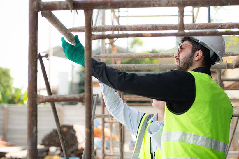 Engineers wearing safety vests and hard hats on a construction site. - engineer vs architect