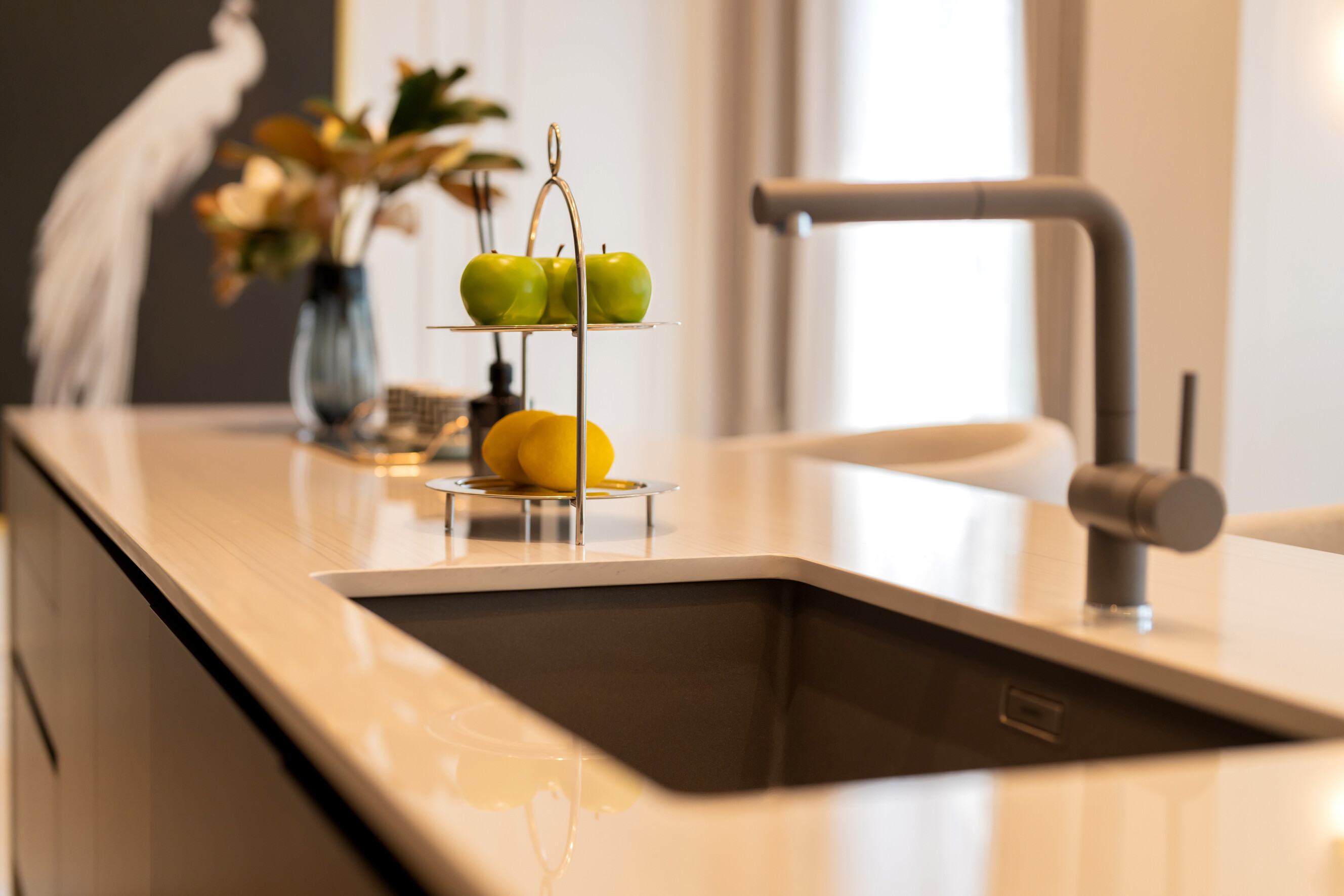 Minimalist kitchen design featuring a sink and decorative fruit stand.