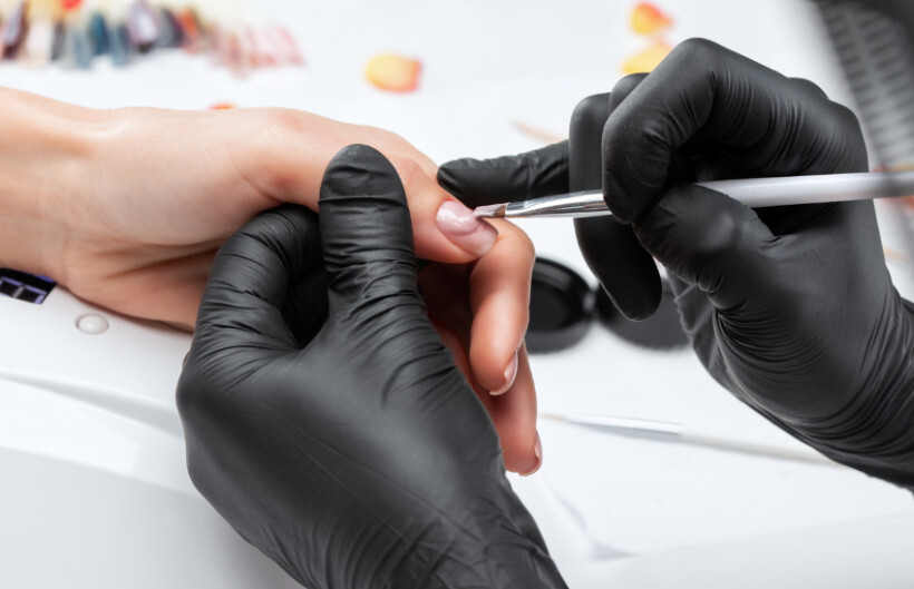 hard gel vs builder gel - nail technician applying gel to a client's nail with precision brushwork