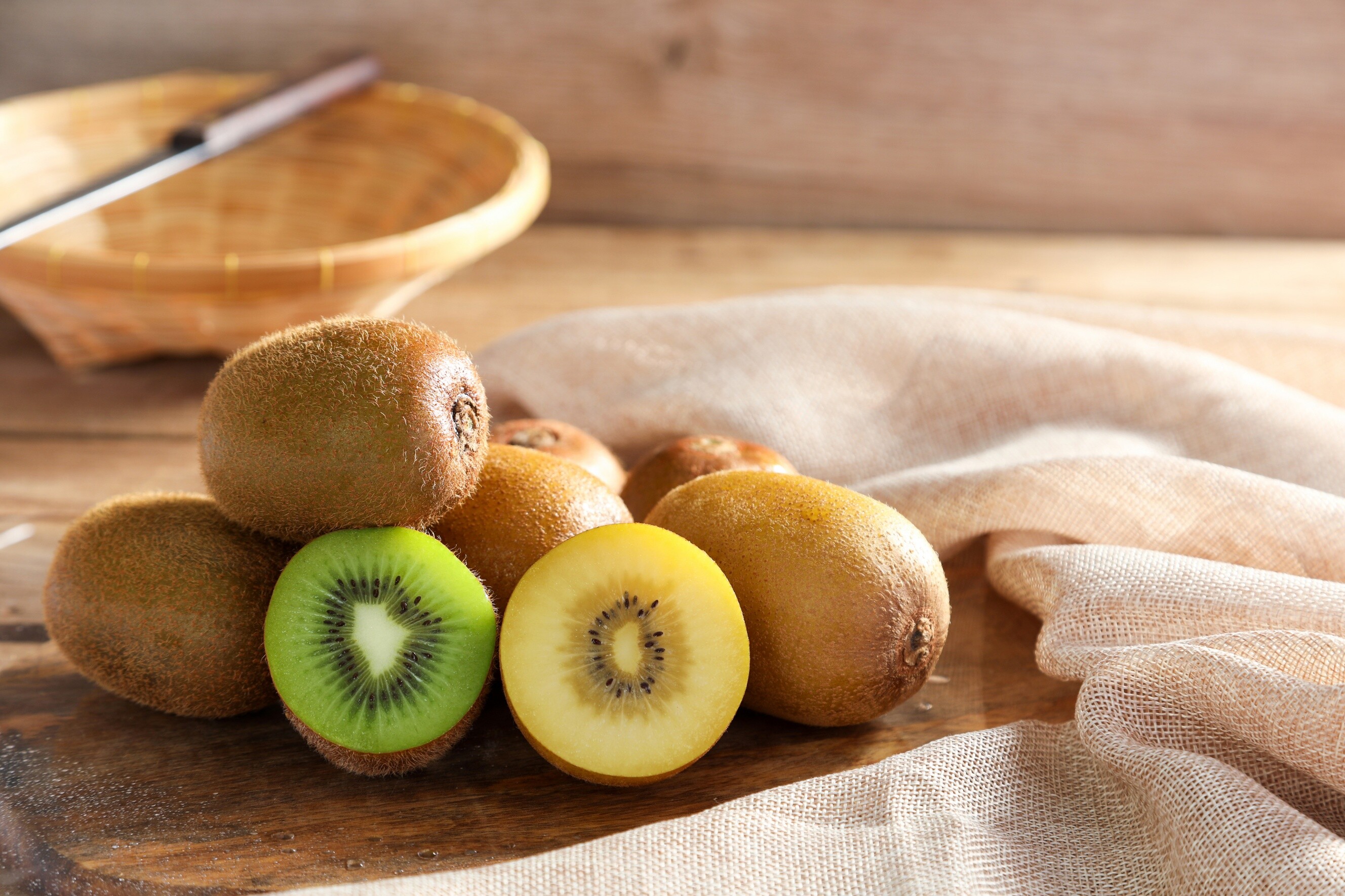 Fresh golden and green kiwi fruits arranged on a wooden plate