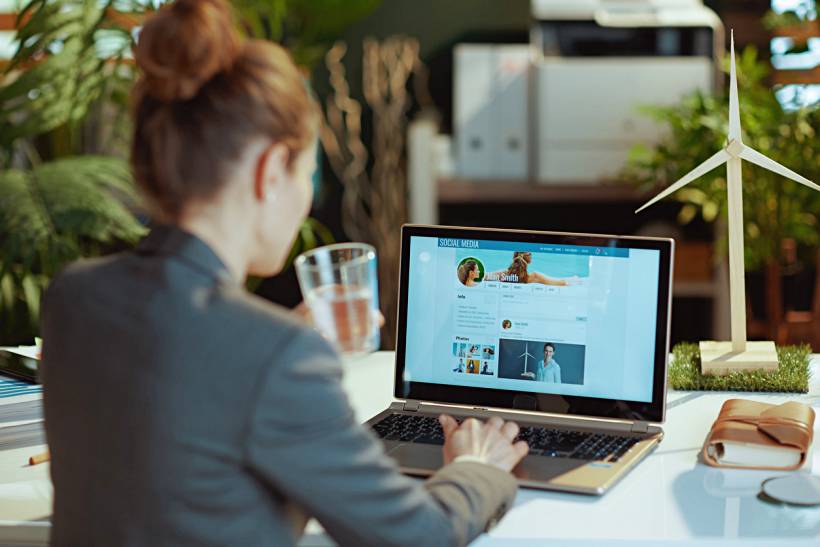 personal assistant vs virtual assistant - Virtual assistant managing social media accounts on a laptop in an office setting.