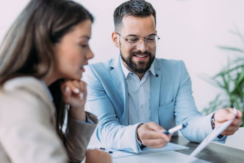 personal assistant vs virtual assistant - Personal assistant reviewing documents with an executive during a meeting