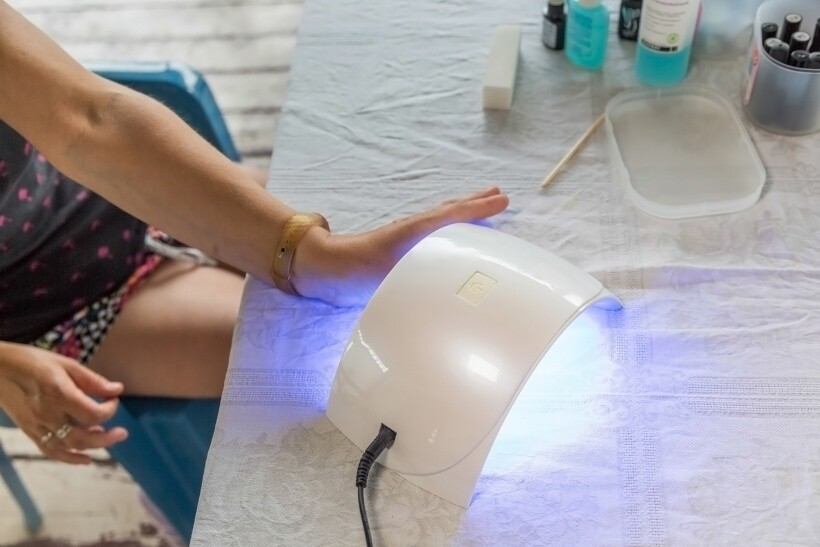 UV nail lamp vs LED nail lamp - Using a UV LED nail dryer with gentle heat emission during a manicure.