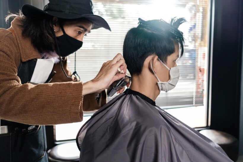 barber vs hairdresser - Barber working carefully on a male client’s haircut indoors.