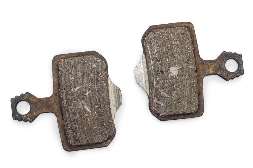 Pair of used sintered brake pads showing wear and metal backing. - sintered vs organic brake pads