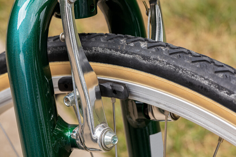 Close-up of bicycle wheel with brake pads pressing against the rim. - organic vs sintered brake pads