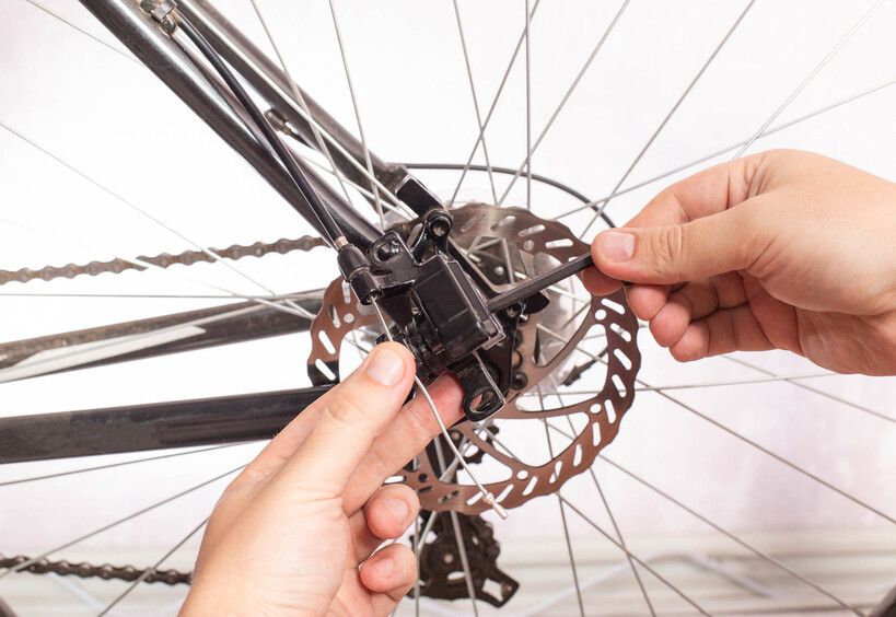 Person aligning brake pads on a bicycle disc brake calliper. - sintered vs organic brake pads