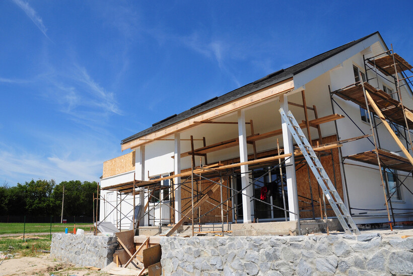 House undergoing renovation with ladders and scaffolding in place. - renovate vs refurbish