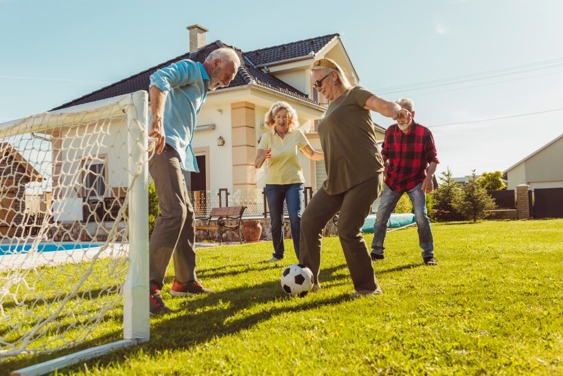 turf vs grass - Family enjoying a soccer game on green grass in a sunny backyard.