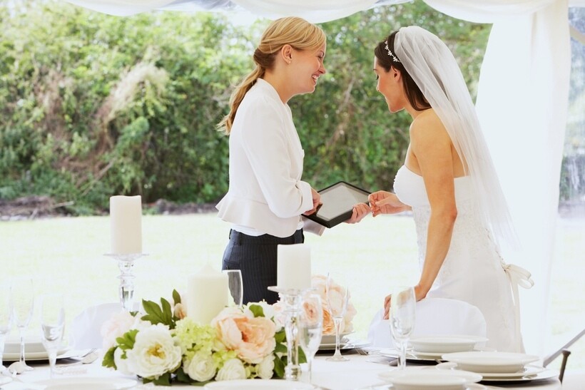 Wedding coordinator consulting with a bride at a decorated reception table. - wedding planner vs coordinator