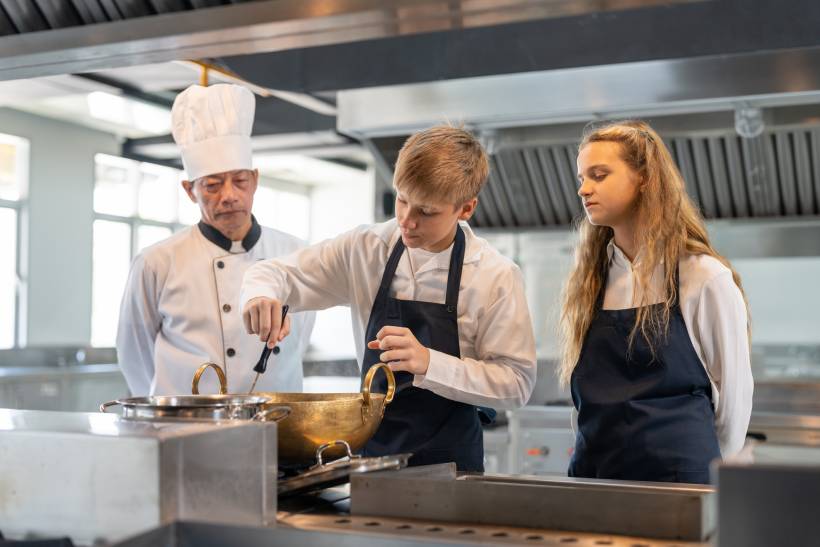 Young culinary students cooking under a chef’s supervision in a commercial kitchen. - chef vs cook