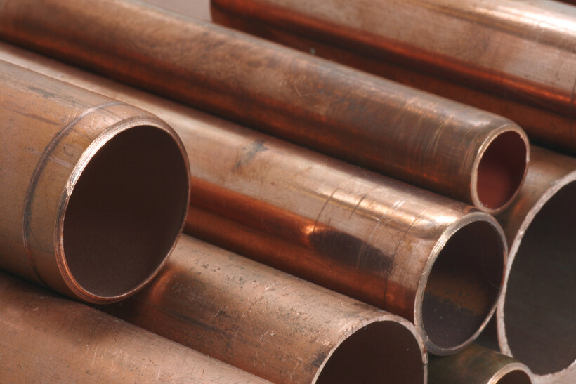 Close-up of shiny copper pipes arranged for construction use. - plastic pvc pipe vs copper pipe