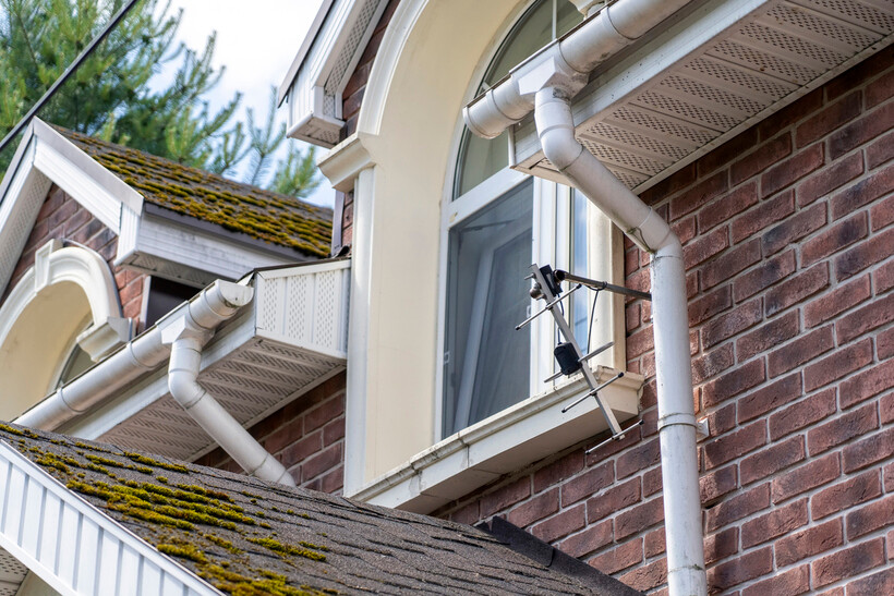 House roof with moss, gutters, and PVC pipes for drainage. - pvc pipe vs copper plumbing