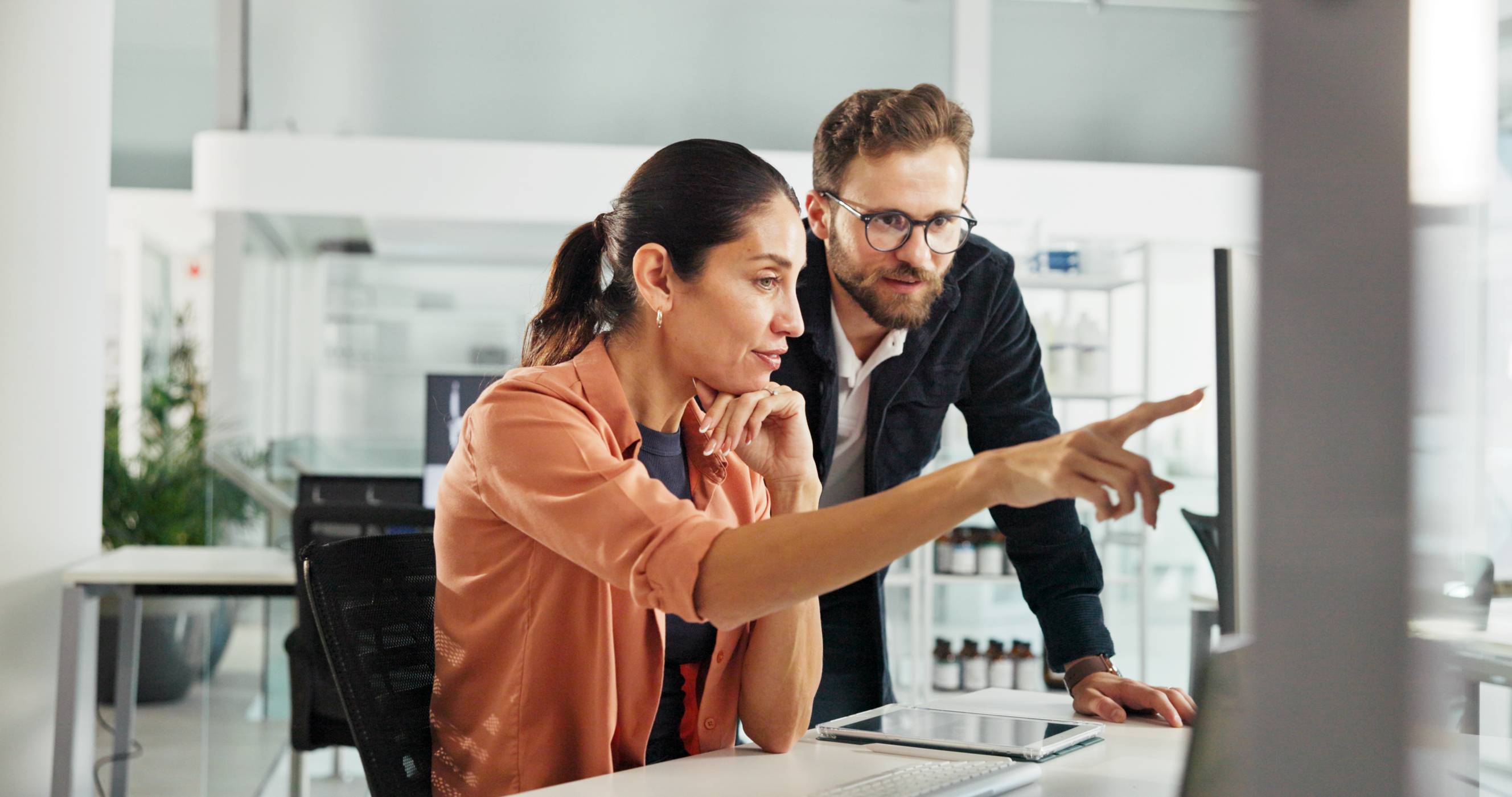 Two colleagues working together, highlighting teamwork in a modern office environment.