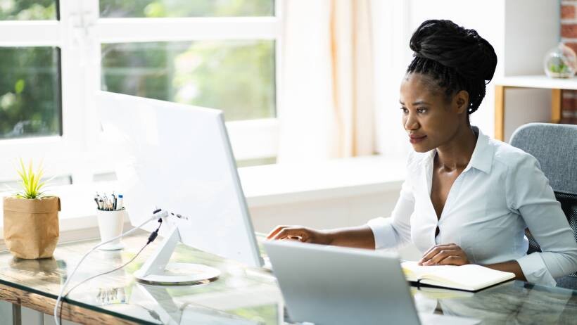 Female software developer working at a desktop computer in an office. - web developer vs software developer
