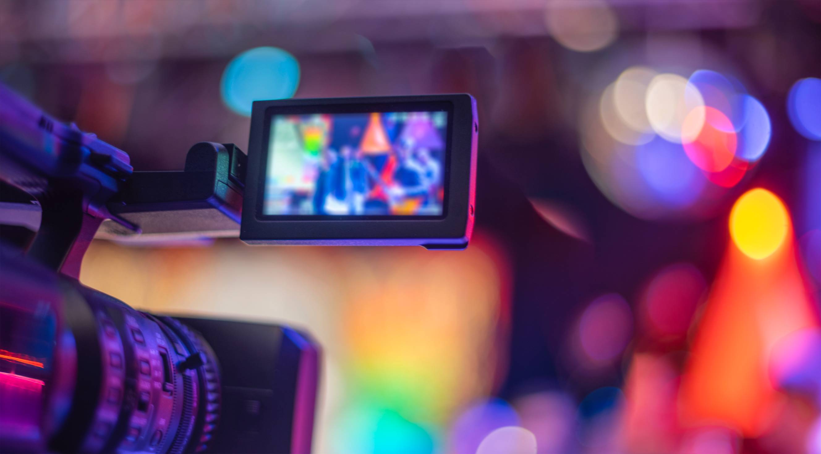 A close-up of a video camera's screen recording a concert with blurry lights in the background.