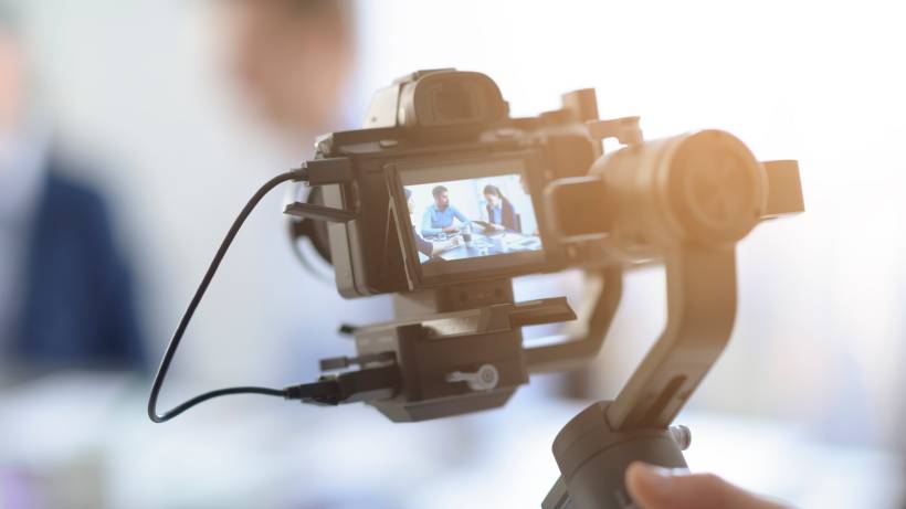 Close-up of a camera's screen showing two people in a meeting being recorded. - videographer vs cameraman