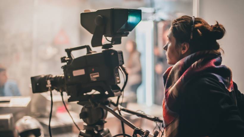 Female cameraman behind a professional video camera on a set. - cameraman vs videographer