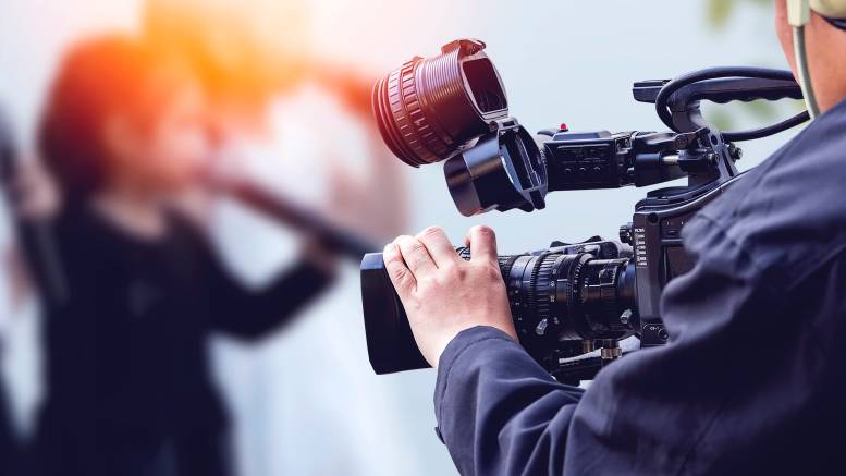 A professional camera operator filming a scene or event with a video camera. - videographer vs cameraman