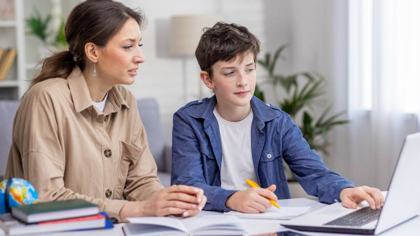 A female tutor providing one-on-one assistance to a student with his homework in a home setting - tutor vs teacher