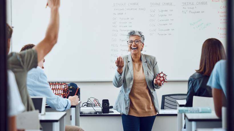 A happy teacher laughing while teaching a science class - tutor vs teacher