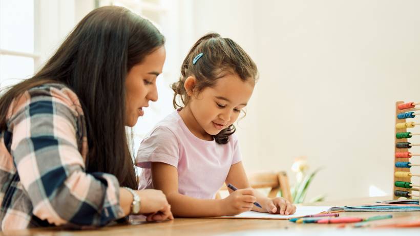 A female private tutor helps a young girl with her drawing. - tutor vs teacher