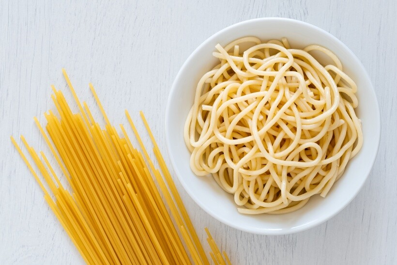 spaghetti vs linguine - bowl of cooked spaghetti next to uncooked spaghetti strands