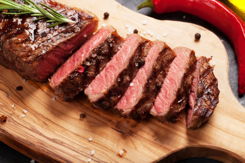 scotch fillet vs porterhouse - cooked porterhouse steaks on a plate with asparagus, roasted potatoes, and herbs