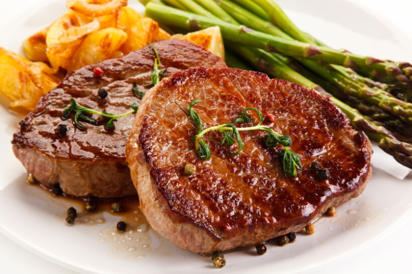 scotch fillet vs porterhouse - sliced medium-rare steak garnished with rosemary on a wooden board