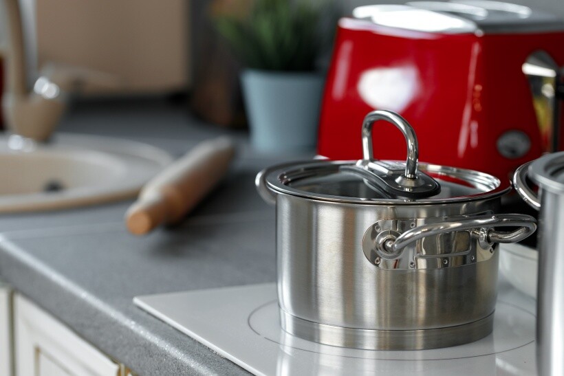 ceramic vs induction cooktop - Stainless steel saucepan on a white induction cooktop.