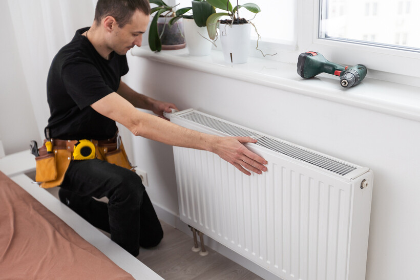Technician installing a radiator connected to a central heating system. - central heating vs electric heater