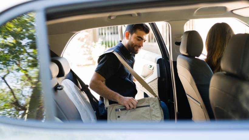 A man getting into the back of a car, ready for his rideshare trip. - make money with a car