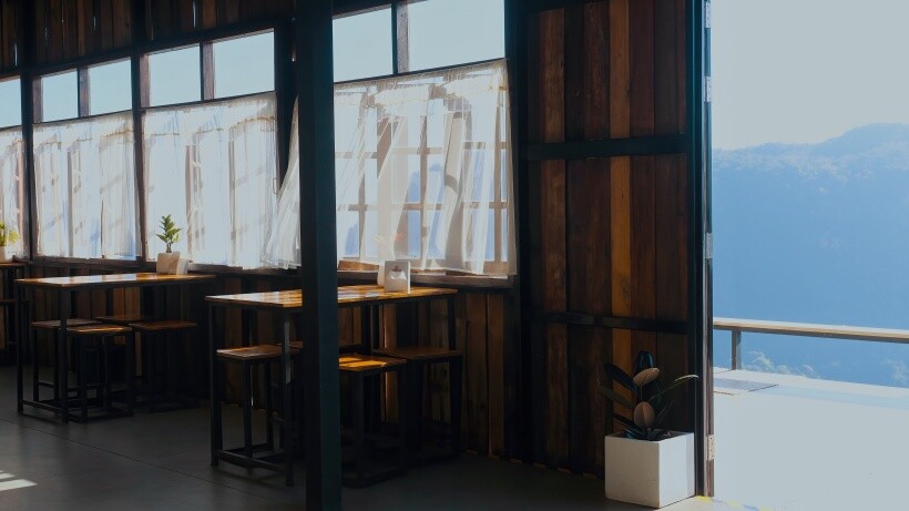 Curtain ideas - Sheer white cafe curtains on large windows in a rustic café