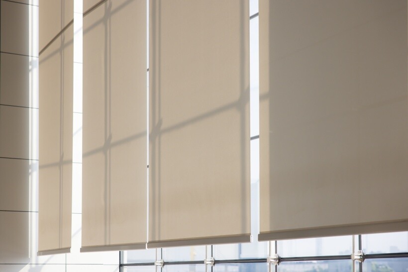 Curtain ideas - Close-up view of beige roller curtains covering tall windows