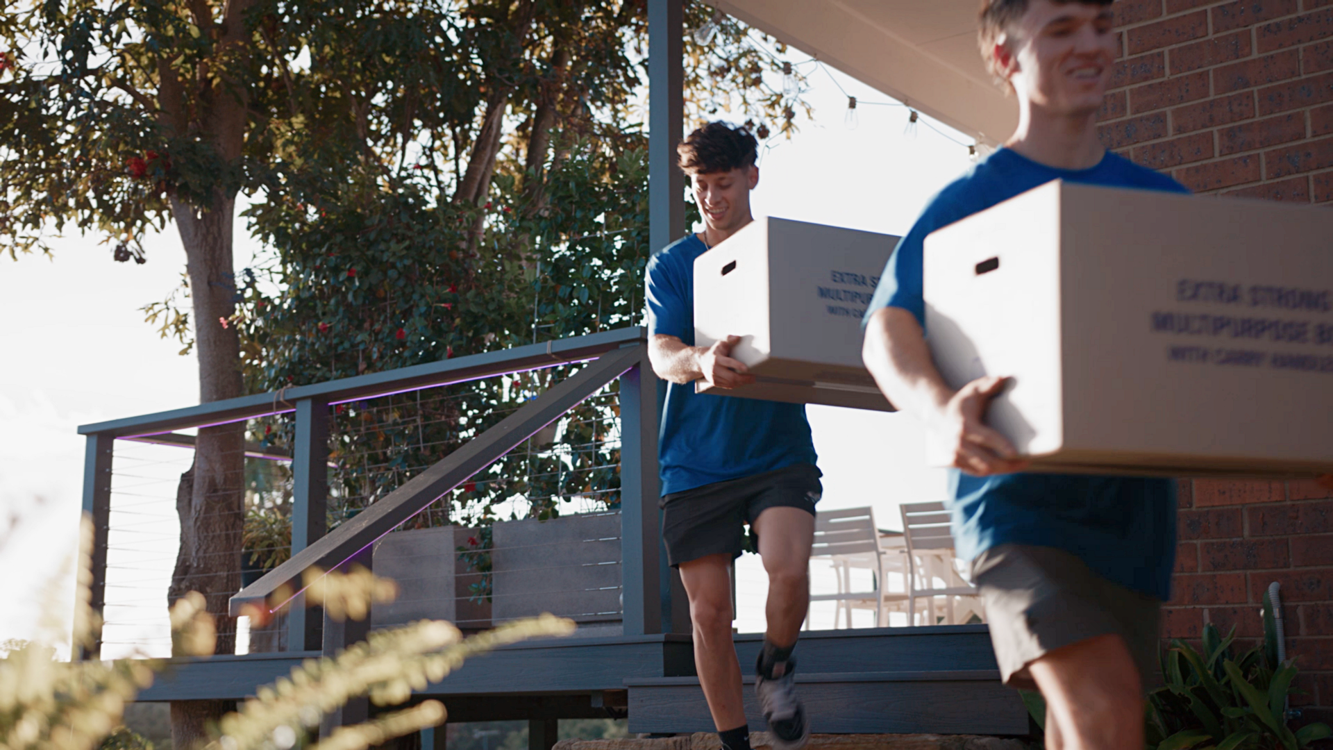 cost to move furniture - Two Taskers carrying large moving boxes down outdoor steps