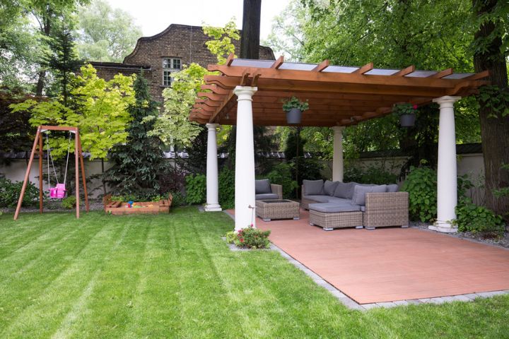 Backyard with a stylish wooden pergola supported by white columns