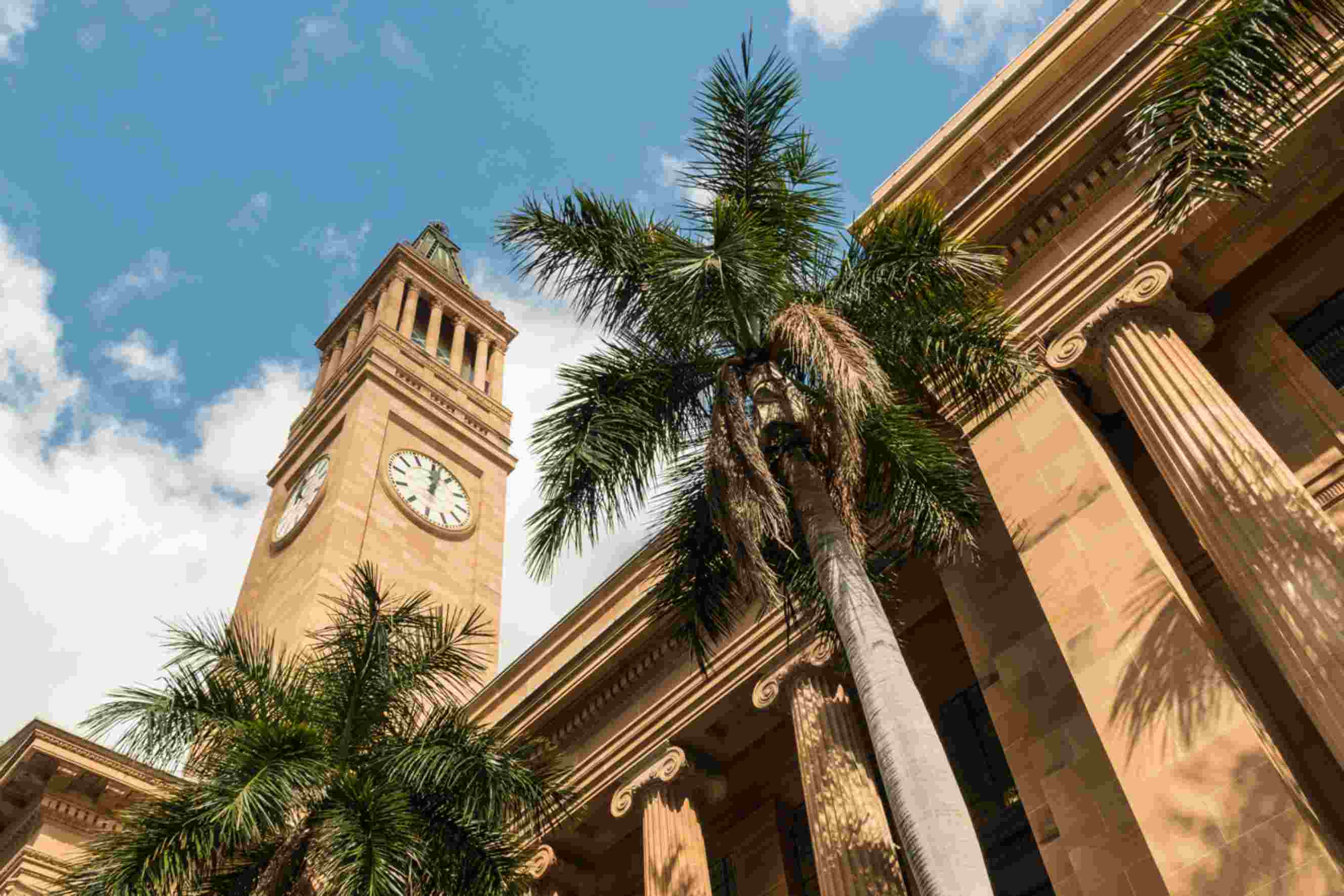 Brisbane City Hall clock tower and palm trees under a blue sky in Queensland, Australia